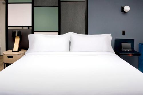 a large bed with white pillows in a bedroom at Aloft Dublin-Pleasanton in Dublin