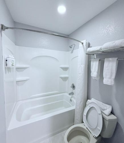 a white bathroom with a toilet and a bath tub at Baymont by Wyndham Grenada in Grenada