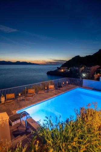 a pool with a view of the ocean at night at Kanakis Apartments in Asos