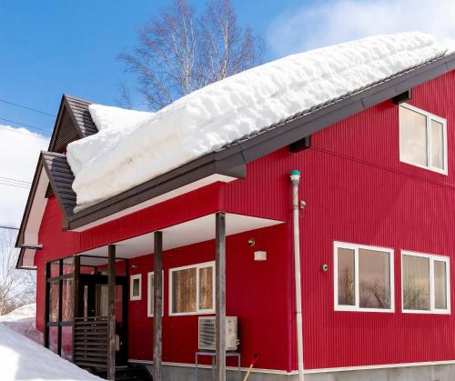 a red house with snow on top of it at niseko / Vacation STAY 4376 in Niseko