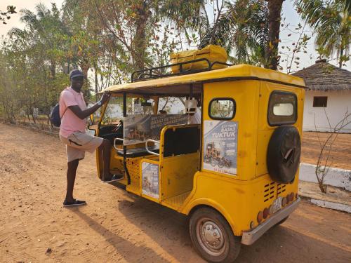 a man is standing next to a yellow food truck at POMBO KUNDA in Sanyang