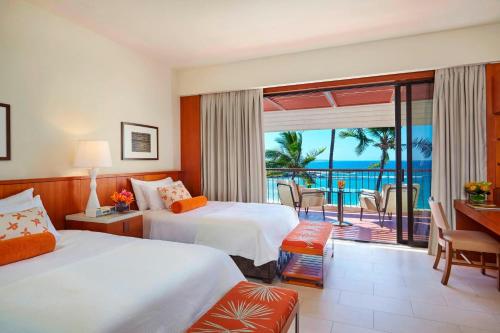 a hotel room with two beds and a balcony at Mauna Kea Beach Hotel, Autograph Collection in Hapuna Beach
