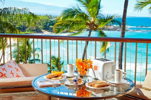 a table with food on a balcony with a view of the ocean at Mauna Kea Beach Hotel, Autograph Collection in Hapuna Beach