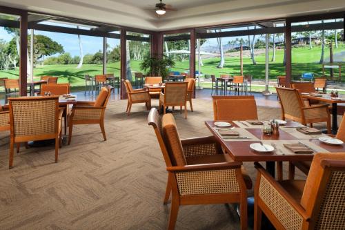 a dining room with tables and chairs and windows at Mauna Kea Beach Hotel, Autograph Collection in Hapuna Beach