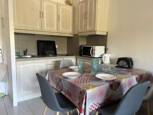 une cuisine avec une table avec des chaises et un micro-ondes dans l'établissement SP400-022 Appt 2 pièces cabine SAINT PIERRE LA MER, à Saint Pierre La Mer