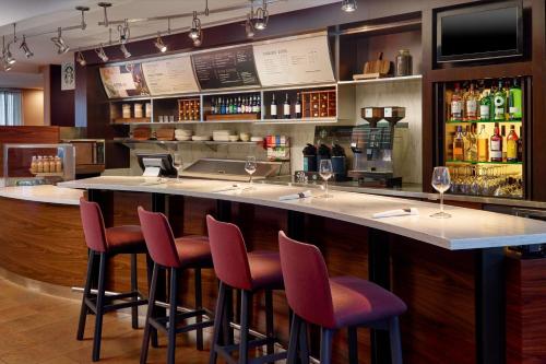 a bar with chairs and a counter with wine glasses at Courtyard by Marriott Atlanta Executive Park/Emory in Atlanta