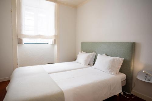 two beds in a small room with a window at Lisbon Story Guesthouse in Lisbon