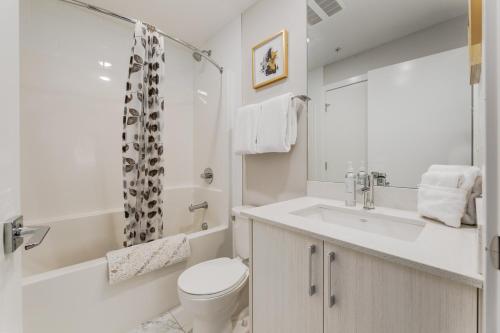 a white bathroom with a toilet and a sink at Inner City Apartment, Pet Friendly, Free Underground Parking in Calgary