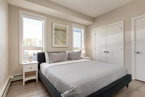 a bedroom with a large bed and two windows at Inner City Apartment, Pet Friendly, Free Underground Parking in Calgary
