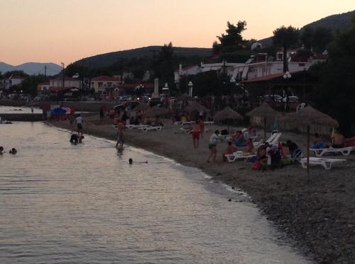 a group of people on the beach at sunset at Despoina Apartments in Edipsos