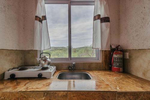 a kitchen counter with a sink and a window at Aguada Escondida in San Marcos Sierras