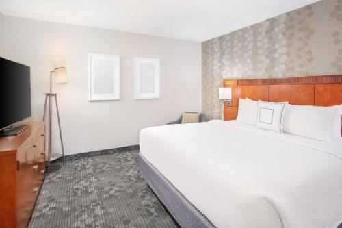 a bedroom with a large bed and a flat screen tv at Courtyard by Marriott Birmingham Homewood in Birmingham