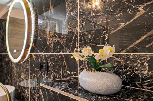 a bathroom with a white vase with flowers on a counter at SEVEN Apartments in Predeal