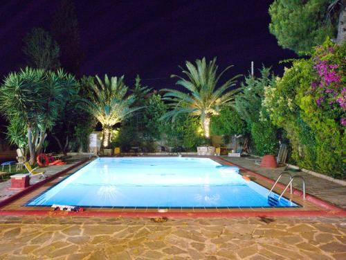 a large swimming pool at night with palm trees at Thomas Beach Hotel in Nea Makri