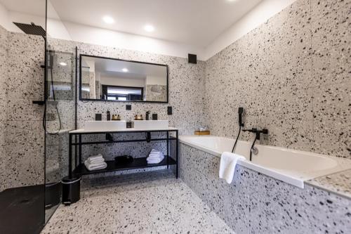 a bathroom with a tub and a sink and a mirror at Hôtel 16 | 150 Montagne & Spa Nuxe in Vars