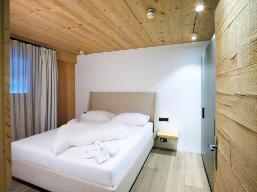 a bedroom with a white bed with a wooden ceiling at SportLodge RACING SUITE - Stylish Apartment with Shared Pool, Whirlpool & Sauna, presented by AlpenLuxus in Kleinboden