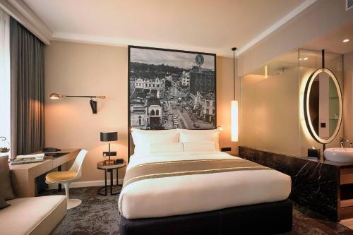 a hotel room with a large bed and a bathroom at Hotel Stripes Kuala Lumpur, Autograph Collection in Kuala Lumpur