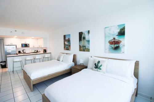 2 camas en una habitación blanca con cocina en Castle 1133 Ocean view studio, Pool and Beach Access, FREE Parking, Tennis and more!, en Miami Beach
