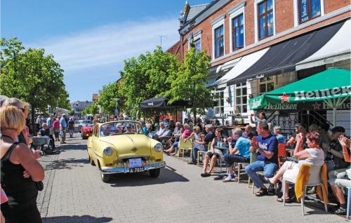 an old yellow car driving down a street with a crowd of people at Apartment Klint Strandvej Nykøbing Sj Vi in Højby