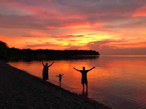 a group of three people standing on the beach at sunset at Lakefront Oak Cottage Hot Tub & Fire Pit in Sodus