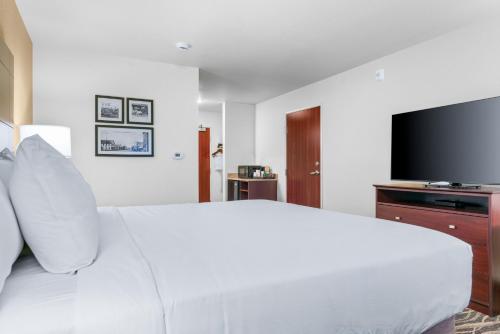 a bedroom with a white bed and a flat screen tv at Cobblestone Hotel & Suites - Lynden in Lynden