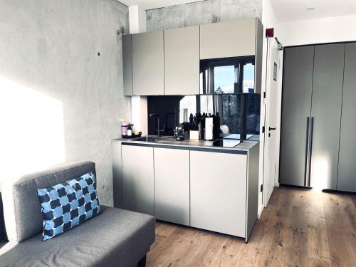 eine Küche mit weißen Schränken und einem Sofa in einem Zimmer in der Unterkunft Mikes Apartments Munich in München