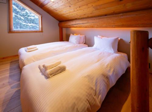 two beds in a room with wooden ceilings at Villa Rusutsu in Rusutsu