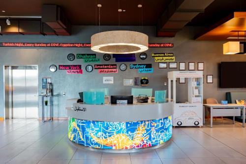 a lobby with a counter with signs on the wall at Aloft Dhahran Hotel in Al Khobar