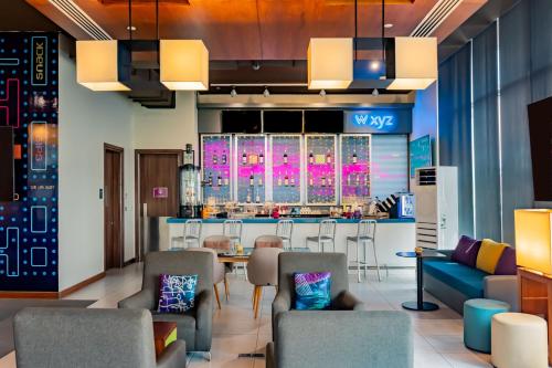 a lobby with a bar with chairs and a table at Aloft Dhahran Hotel in Al Khobar