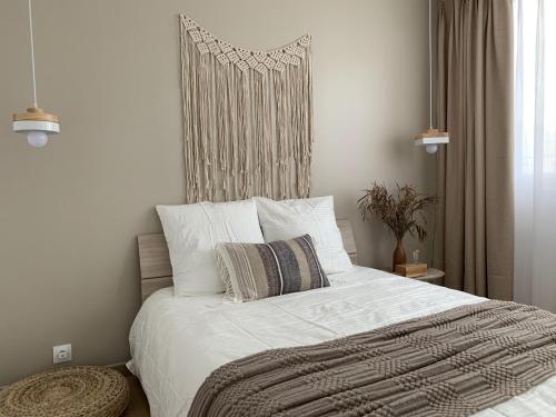 une chambre avec un lit avec des draps blancs et des oreillers dans l'établissement apt lumieuse confor parking free, à Paris