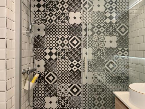 La salle de bains est pourvue d'une douche avec du carrelage noir et blanc. dans l'établissement apt lumieuse confor parking free, à Paris
