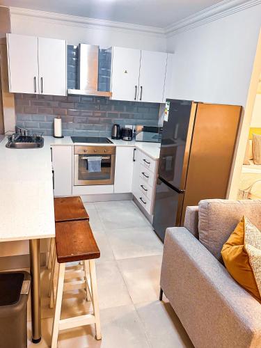 a kitchen with white cabinets and a stainless steel refrigerator at Seapoint escape stylish studio in Cape Town