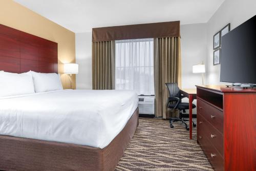 a hotel room with a bed and a desk and a television at Cobblestone Hotel & Suites - Lynden in Lynden