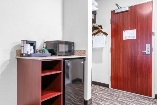 a room with a desk with a microwave and a door at Cobblestone Hotel & Suites - Lynden in Lynden