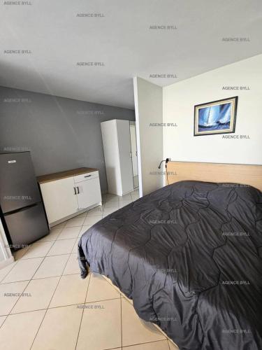 sypialnia z łóżkiem z czarną kołdrą w obiekcie Résidence Héliopolis Bâtiment E - STUDIO 2 pers. HELIOPOLIS Bâtiment E MAE-5494 w Cap d'Agde