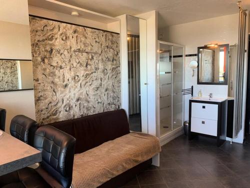 d'un salon avec un canapé brun et d'une salle de bains. dans l'établissement Résidence Héliopolis Bâtiment Ab - Studio 2 pers. - Héliopolis Bât. AB MAE-4644, au Cap d'Agde