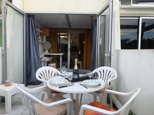 - une table blanche avec des chaises et une bouteille de vin dans l'établissement Résidence Port Nature Colline 2 - Studio- Port Nature Colline 2 - 2 pers. MAE-6641, au Cap d'Agde