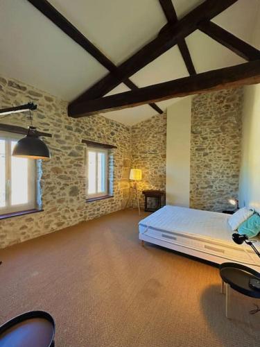 - une chambre avec un lit dans une pièce dotée de murs en pierre dans l'établissement La Maison Cardau, à Névian