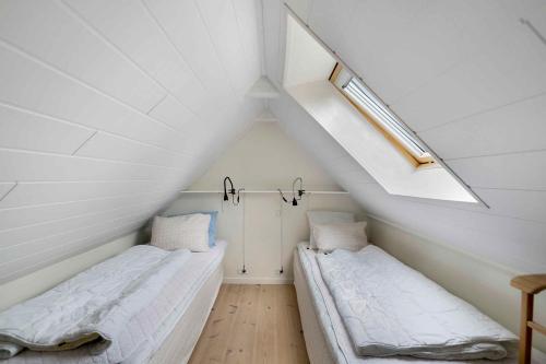 NeksøにあるCozy Holiday Home On Sydbornholmの傾斜した天井の白い部屋にベッドが2つある