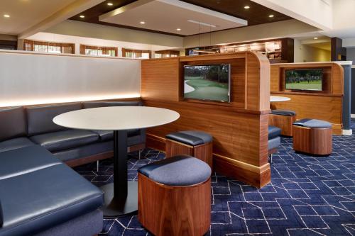 a waiting room with a tv and a table andools at Courtyard by Marriott Charlottesville in Charlottesville