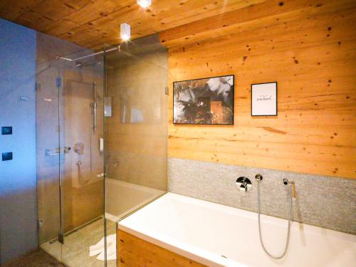 a bathroom with a shower and a bath tub at SportLodge RACING SUITE - Stylish Apartment with Shared Pool, Whirlpool & Sauna, presented by AlpenLuxus in Kleinboden