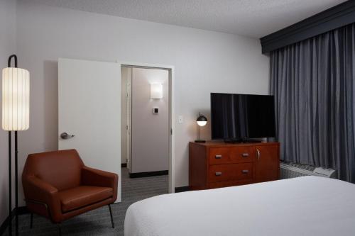 a hotel room with a bed and a chair and a television at Courtyard Denver Tech Center in Greenwood Village