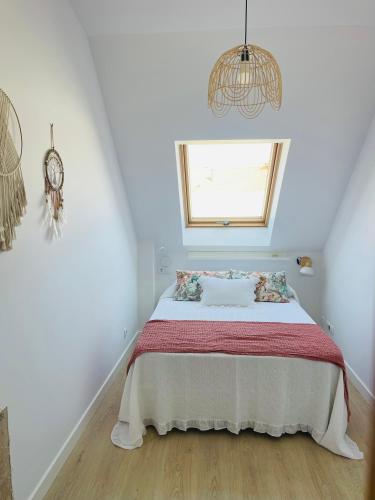 a white bedroom with a bed with a window at Piso en calle peatonal. in Boiro