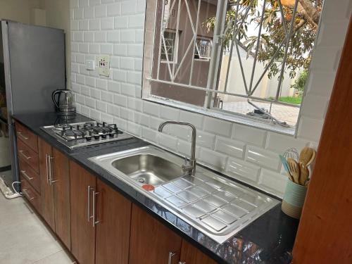 un bancone da cucina con un lavandino e una finestra di Mango cottage a Lusaka