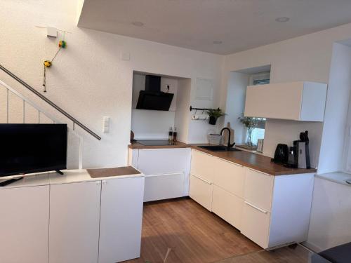 a kitchen with white cabinets and a flat screen tv at Traumhaft moderne Ferienhaus-Tiny House in 78554 Aldingen in Aldingen
