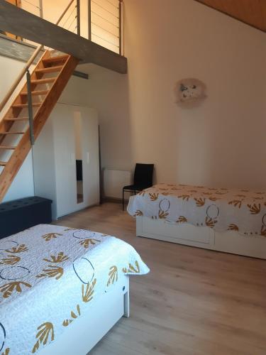 a bedroom with two beds and a staircase at Gîte les Griffons in Clairvaux-les-Lacs