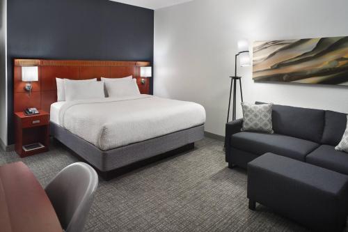 a hotel room with a bed and a couch at Courtyard Charlotte Arrowood in Charlotte