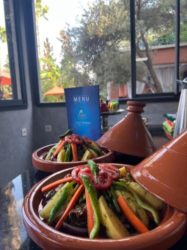 two dishes of vegetables on a table with a menu at RIAD REDWAN in Marrakech