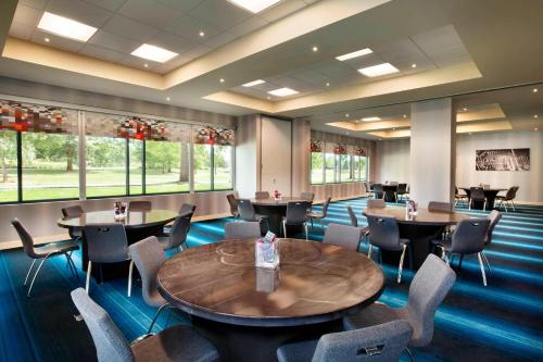 a dining room with tables and chairs and windows at Aloft Hillsboro-Beaverton in Hillsboro