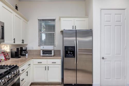 a kitchen with a stainless steel refrigerator and white cabinets at Music Lovers Paradise 7 Bed Pool Home and Game Room in Indio